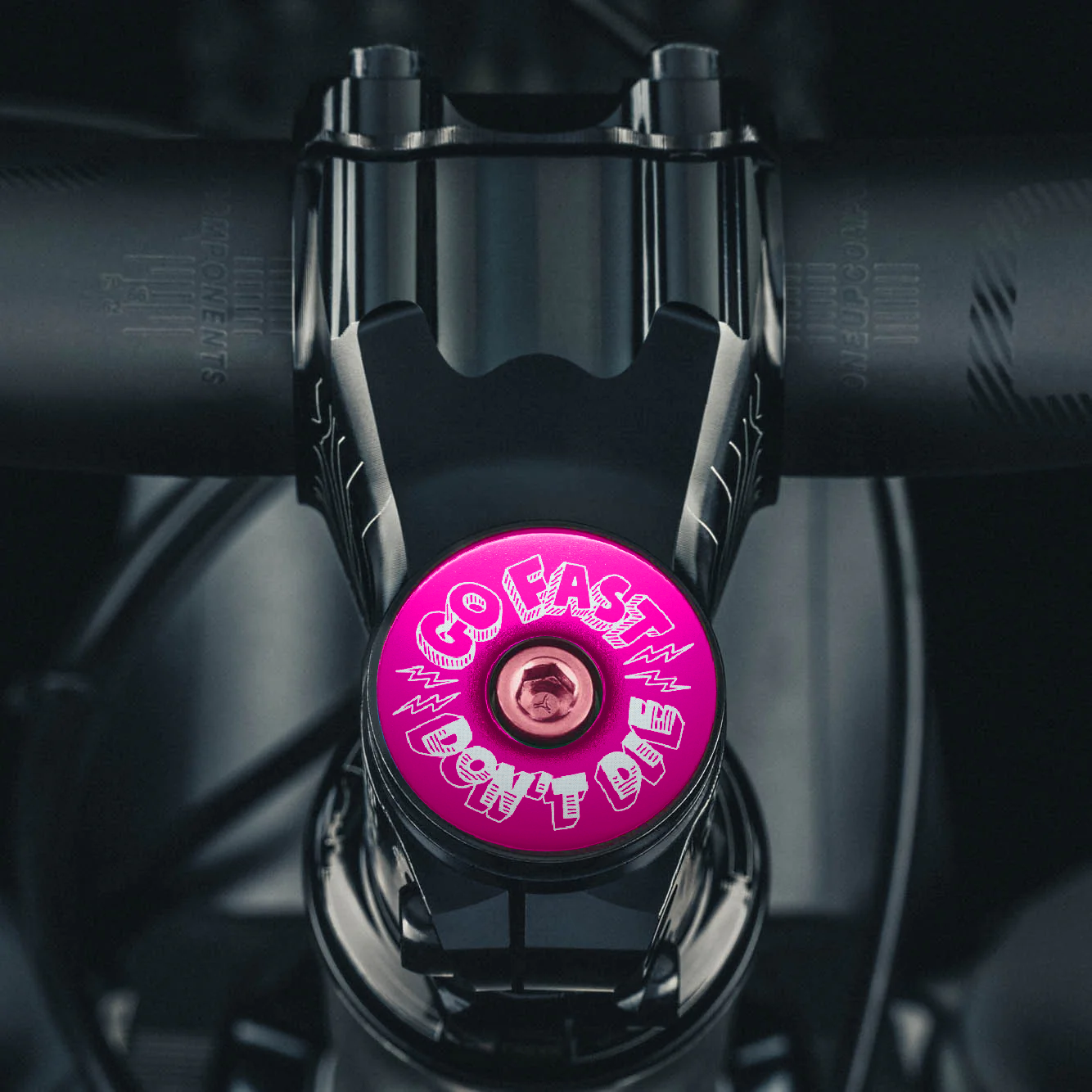 Hot pink bicycle stem cap designed for adventure seekers living the Go Fast Don’t Die lifestyle.