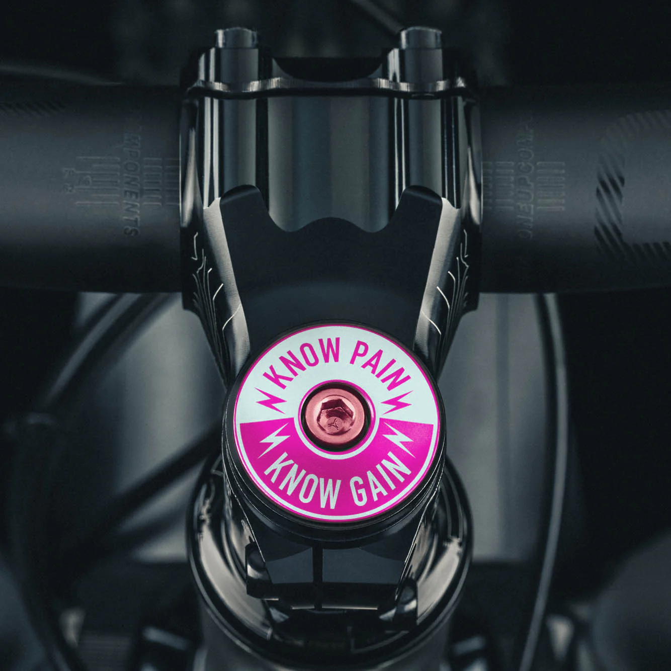 Pink Know Pain Know Gain bicycle stem cap, symbolizes strength and perseverance.