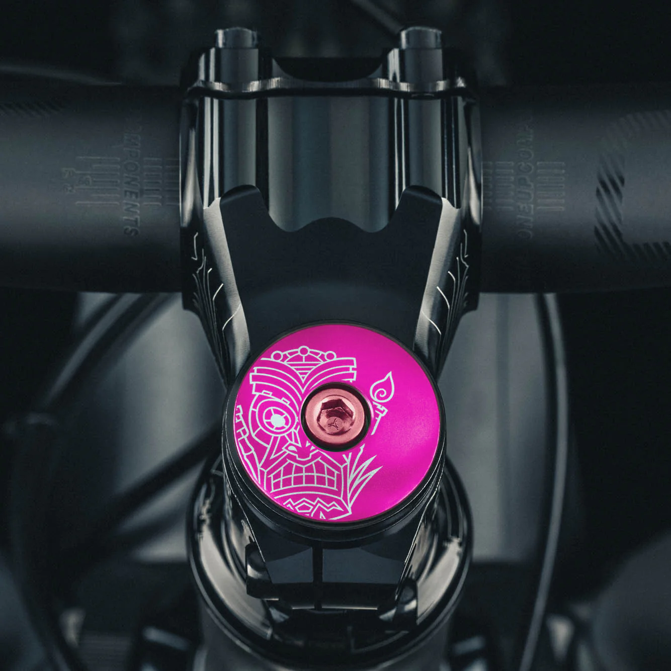 Hot pink bicycle top cap with a tiki design for 1 1/8-inch steerer tubes made from aluminum.