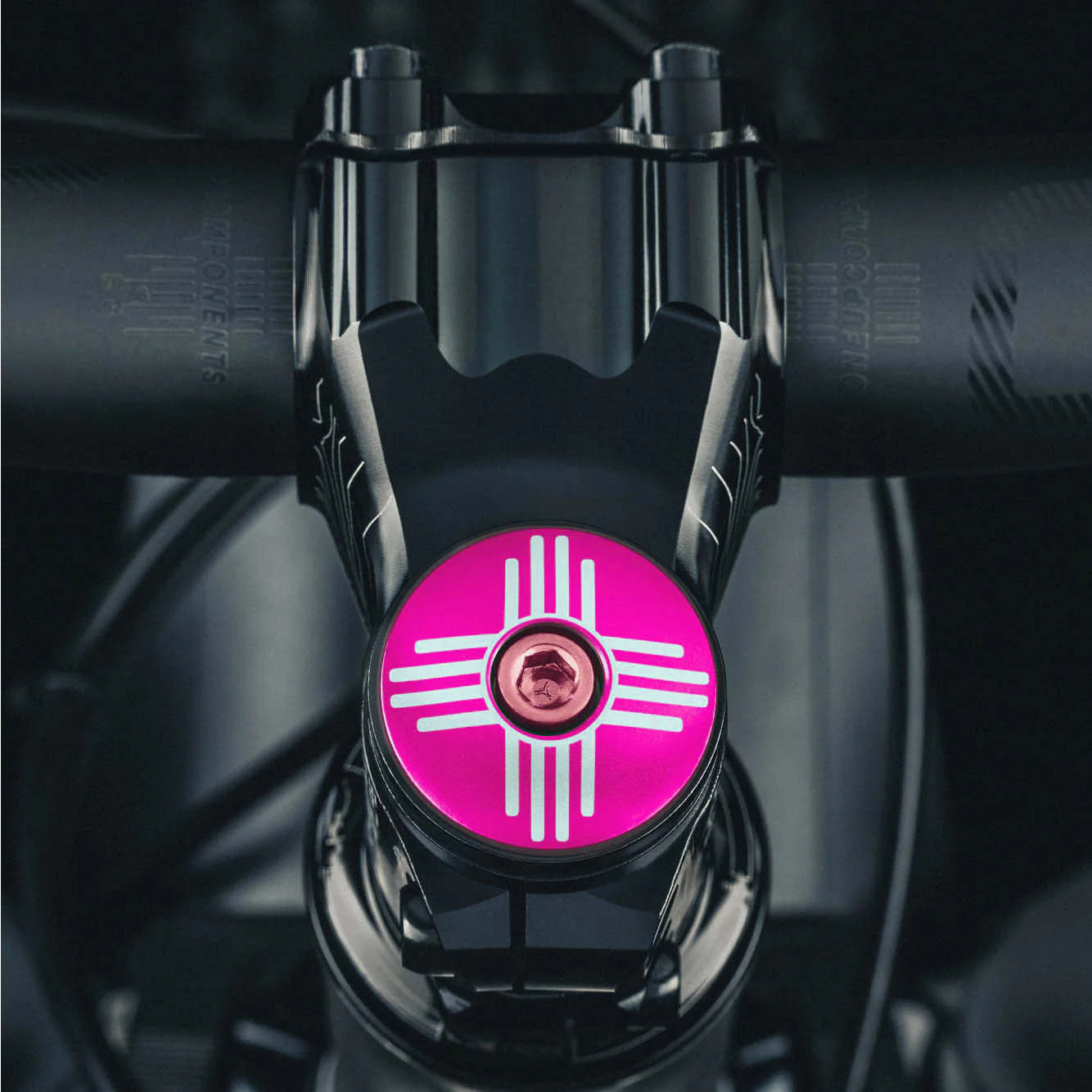 Hot pink custom stem cap with Zia symbol, perfect for personalizing your bike accessories.