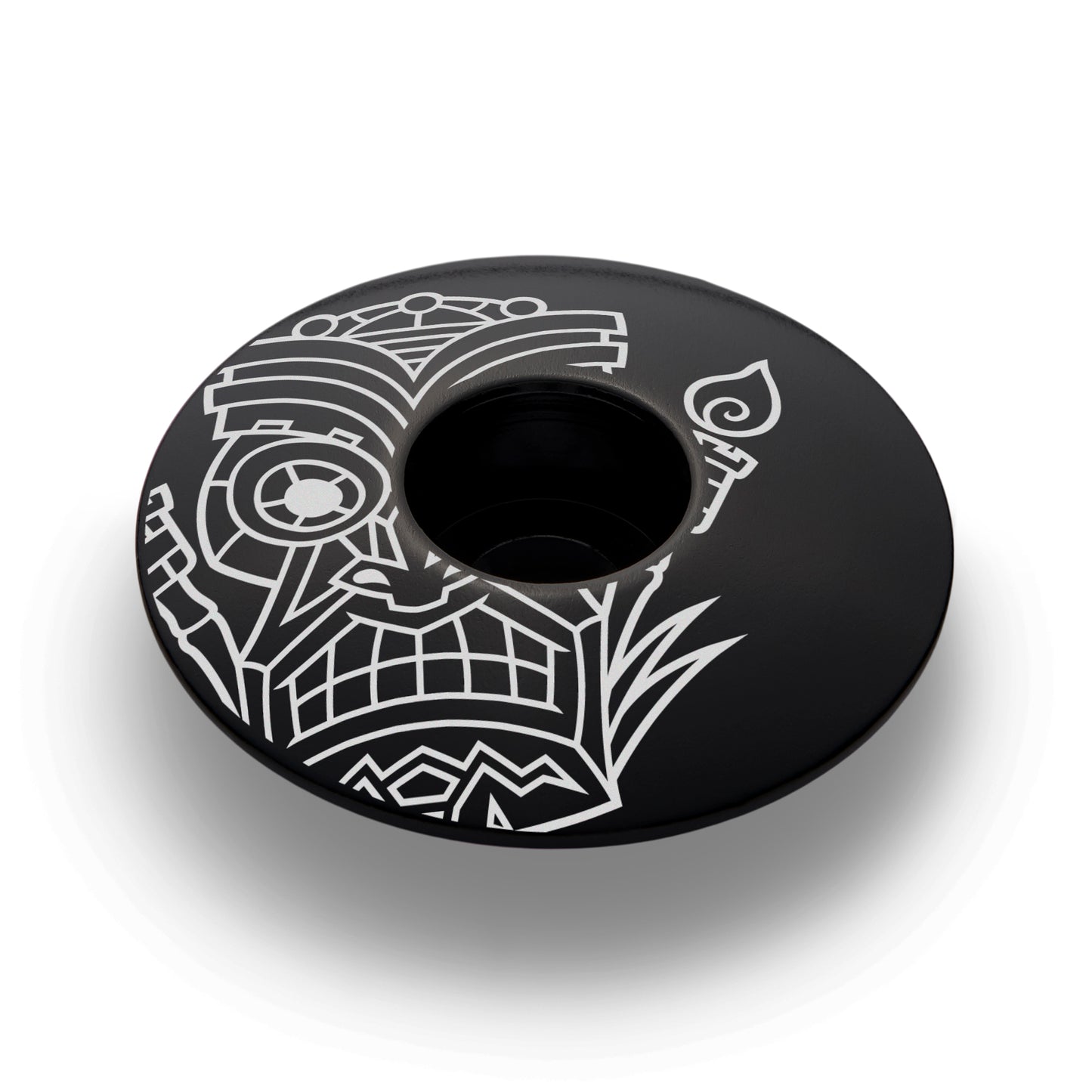 Black bicycle headset cap with a tiki-inspired design for 1 1/8-inch steerer tubes made of lightweight aluminum.