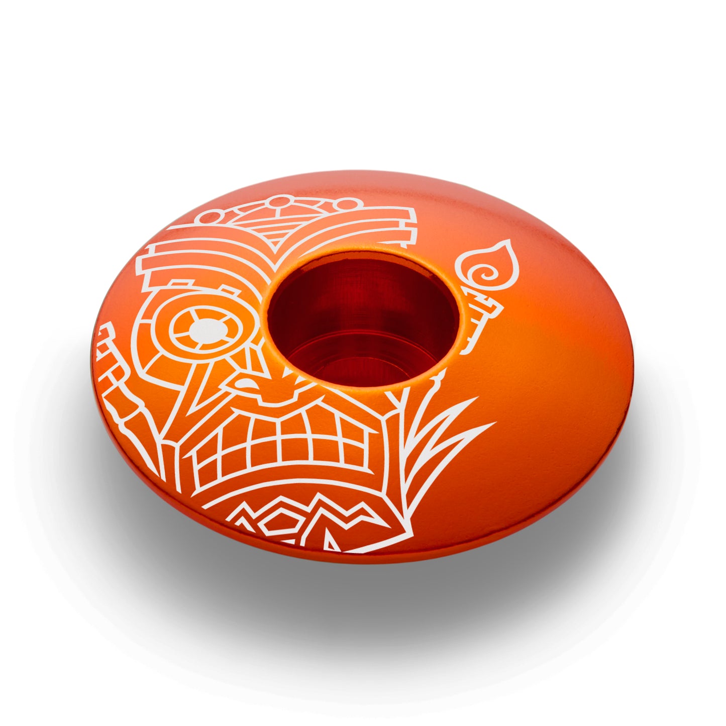 Orange bicycle headset cap with a tiki pattern made of strong and lightweight aluminum.