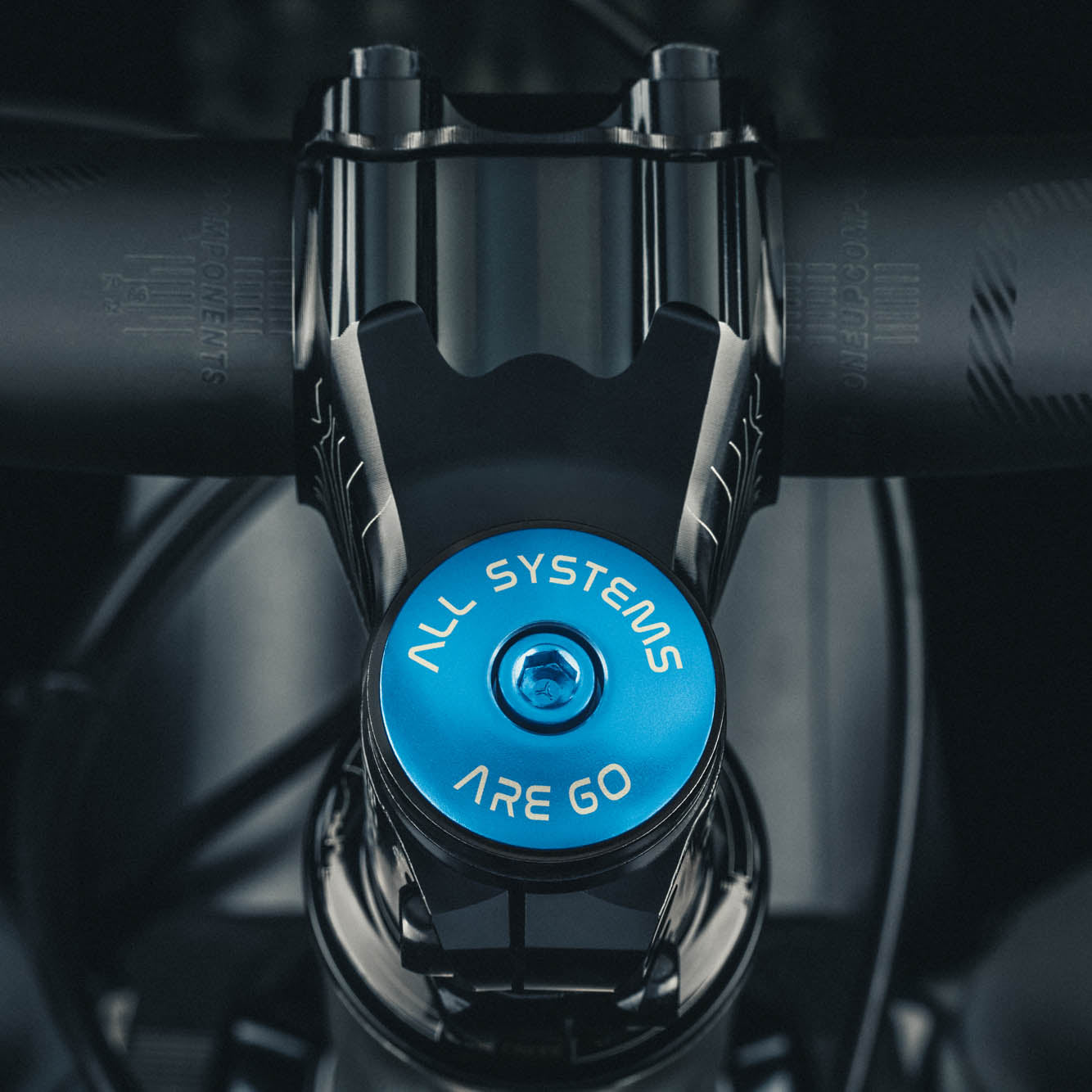Blue anodized bike stem cap featuring "All Systems Are Go" design for cycling enthusiasts.