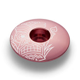 Orange bicycle headset cap with a tiki pattern made of strong and lightweight aluminum.